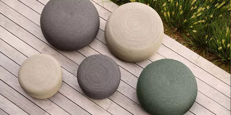 Cane-line Circle Teppiche in Grau, Beige und Grün auf Holzterrasse, Vogelperspektive, stimmungsvolle Gartenatmosphäre.