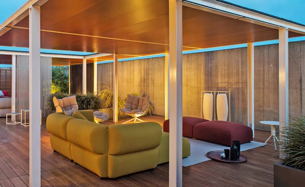 B&B Italia Butterfly Gartenmöbel Loungegruppe auf einer modernen Terrasse mit Holzboden und Überdachung bei Sonnenuntergang.