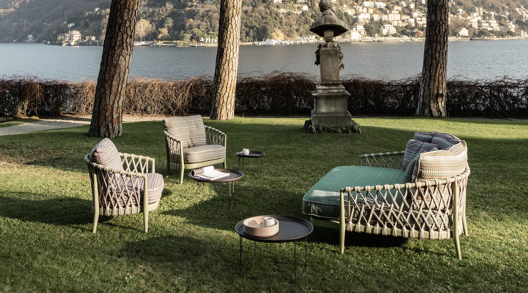 B&B Italia Erica 19 Outdoor Lounge auf einer Wiese mit Blick auf einen See und Bäume im Hintergrund Mood Bild mit Gartenmöbeln und Beistelltischen