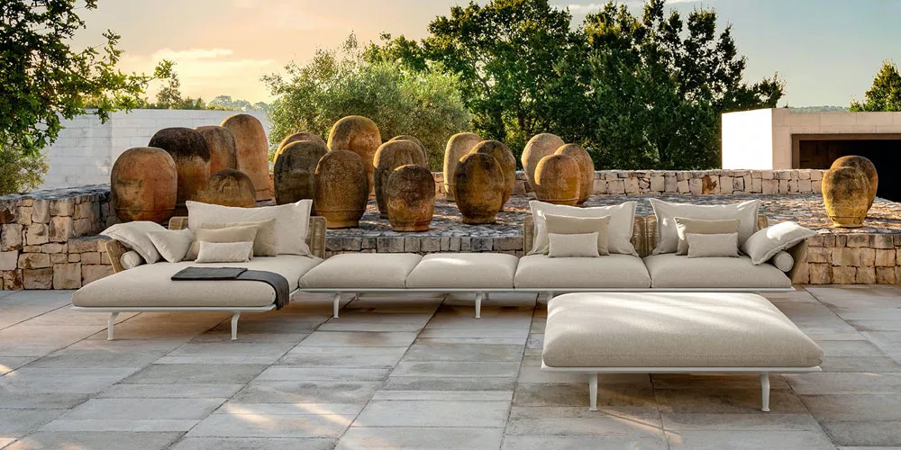 Talenti Cruise Alu Kollektion in Beige auf einer Terrasse mit Steinmauern und antiken Krügen im Hintergrund, stimmungsvolle Abendstimmung.