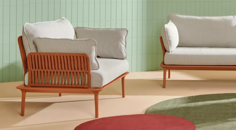 Zwei Loungesessel von Pedrali in Weiß und Terrakotta auf beigem Boden vor mintgrüner Wand, in entspannter Wohnzimmeratmosphäre.