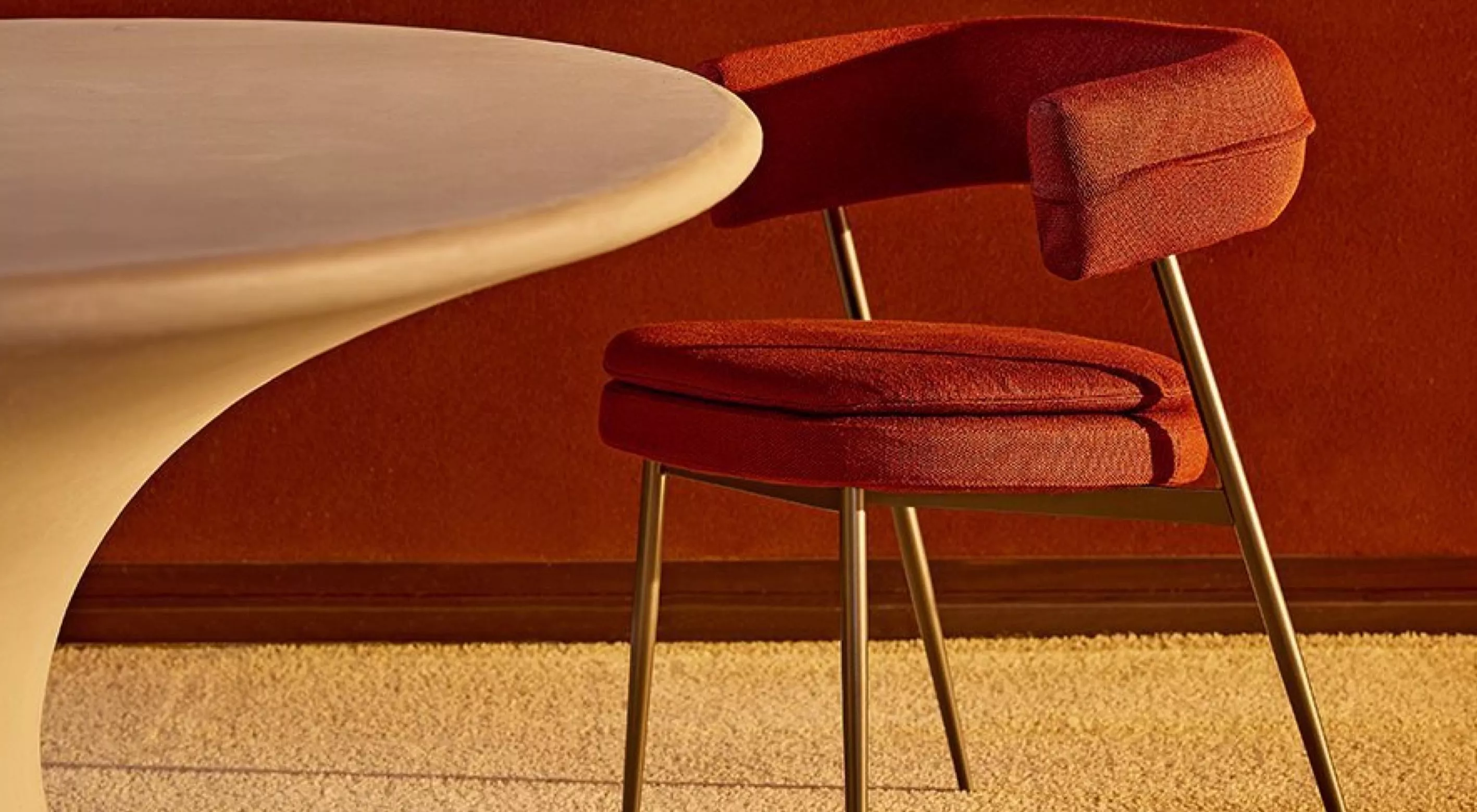 Roter Nena-Stuhl von Villa Schmidt neben einem runden Tisch auf beigem Teppich in warm beleuchtetem Raum.