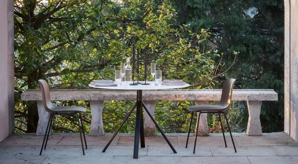 Lapalma FORK Outdoor Essgruppe in Schwarz und Weiß auf einer Steinterrasse vor einem grünen, bewaldeten Hintergrund.