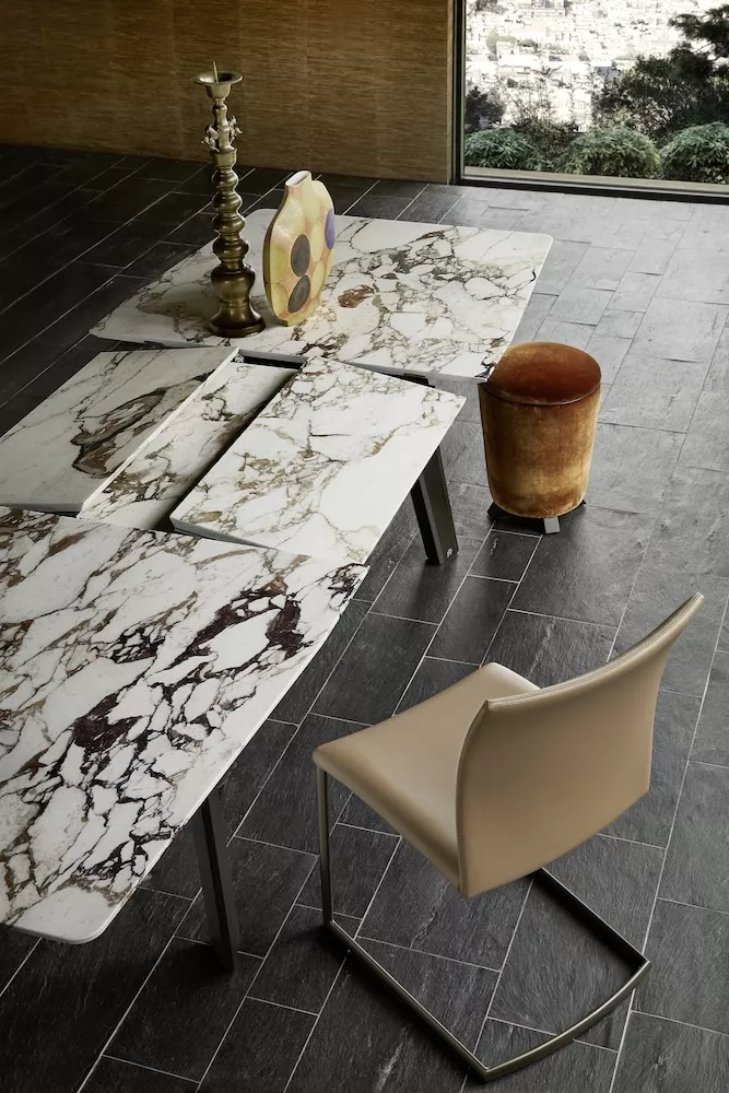 Fontana Tisch von Draenert in einem modernen Raum mit Marmortischplatte und Stuhl in Lederoptik Moodbild mit Blick auf die Stadt im Hintergrund