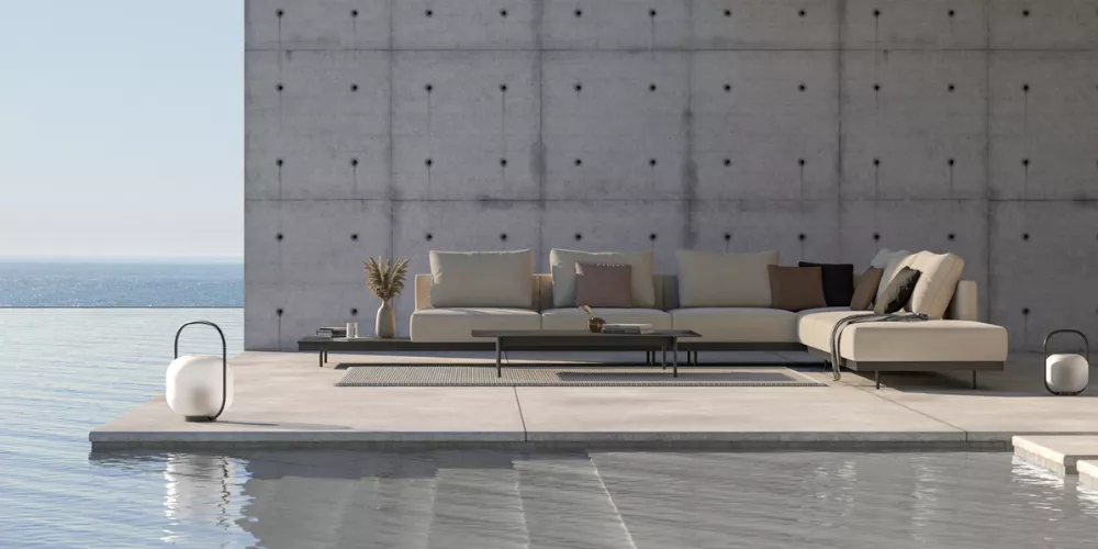 Moderne Outdoor-Lounge von Villa Schmidt, beige, auf Betonterrasse mit Meerblick, stimmungsvolles Ambiente.