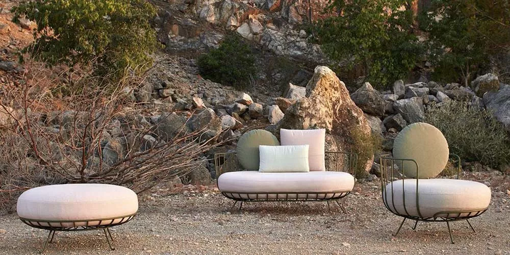 Calma Lou Outdoor-Möbelset in Beige und Grün auf steinigem Hintergrund in natürlicher Umgebung.