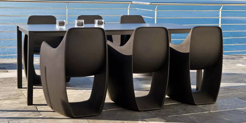 Calma Gat Esstisch-Set in Schwarz auf einer Terrasse mit Meerblick, bestehend aus einem Tisch und vier Stühlen, modernes Design.