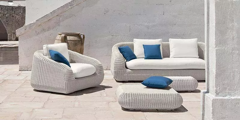 Ethimo Phorma Outdoor-Loungegruppe in Weiß mit blauen Kissen auf einer Terrasse vor einer weißen Wand.