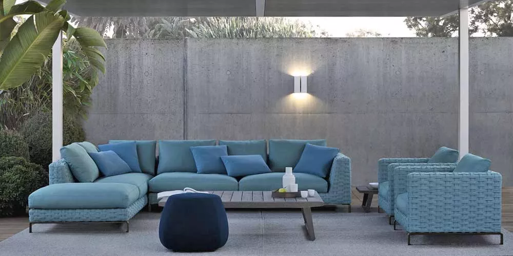 B&B Italia Ray Outdoor Loungegruppe Loungesofa in Blau auf einer Terrasse mit Betonwand im Hintergrund und Pflanzen im Vordergrund