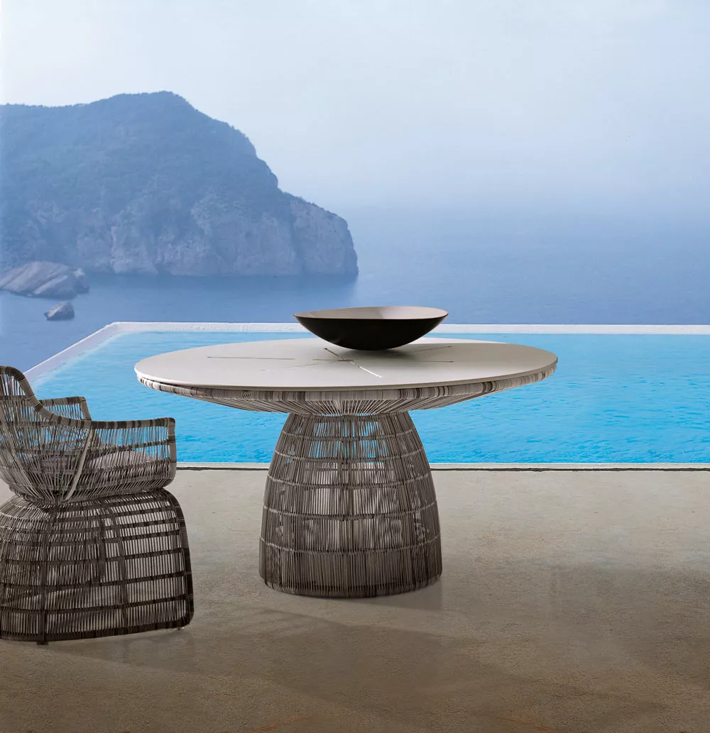 B&B Italia Crinoline Outdoor Essgruppe vor einem Infinity-Pool mit Blick auf das Meer und eine felsige Küste im Hintergrund