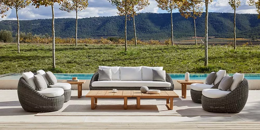 Gartenmöbel-Set von Point Heritage in Grau und Weiß auf einer Terrasse mit Bergblick und Pool im Hintergrund.