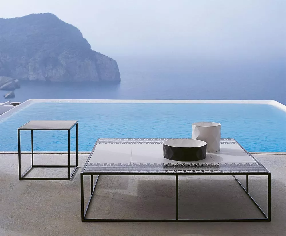 B&B Italia Canasta Outdoor Loungtische stehen auf einer Terrasse mit Blick auf das Meer und einen Infinity-Pool im Hintergrund