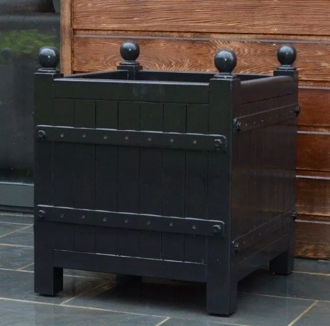 Orangerie Pflanzkübel aus lackiertem Akazienholz steht auf einer Terrasse vor einer Holzwand und ist für den Außenbereich geeignet