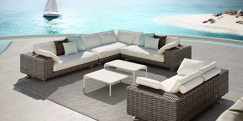 Dedon Paros Kollektion auf einer Terrasse mit Blick auf das Meer und einem Segelboot im Hintergrund