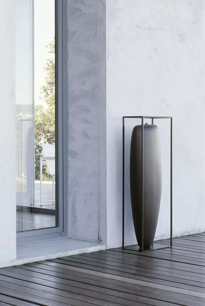 B&B Italia Overscale Flames Outdoor Kerze steht in einem modernen Außenbereich neben einer Glastür auf einer Holzterrasse.