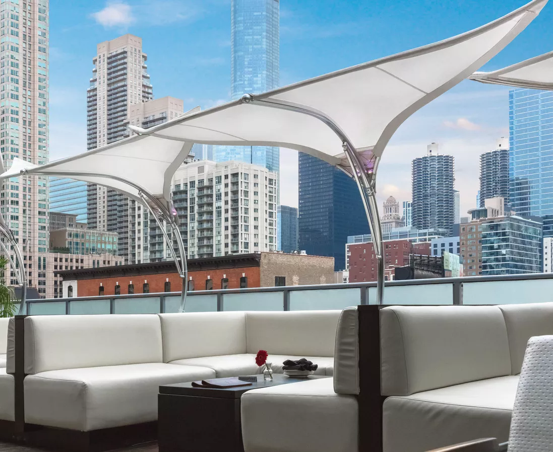 Tuuci Stingray Sonnenschirm in Weiß auf einer modernen Dachterrasse mit Stadtblick und weißen Loungemöbeln.