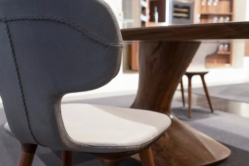 RIVA1920 Stuhl in Grau und Weiß, Detailansicht in modernem Esszimmer mit Holztisch im Hintergrund.