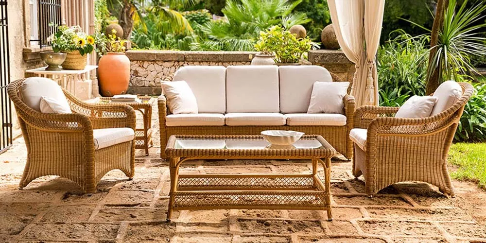 Point Arena Outdoor Loungegruppe in Naturfarbe auf einer Terrasse mit Steinboden und Pflanzen im Hintergrund, bestehend aus Sofa, Sesseln und Tisch.