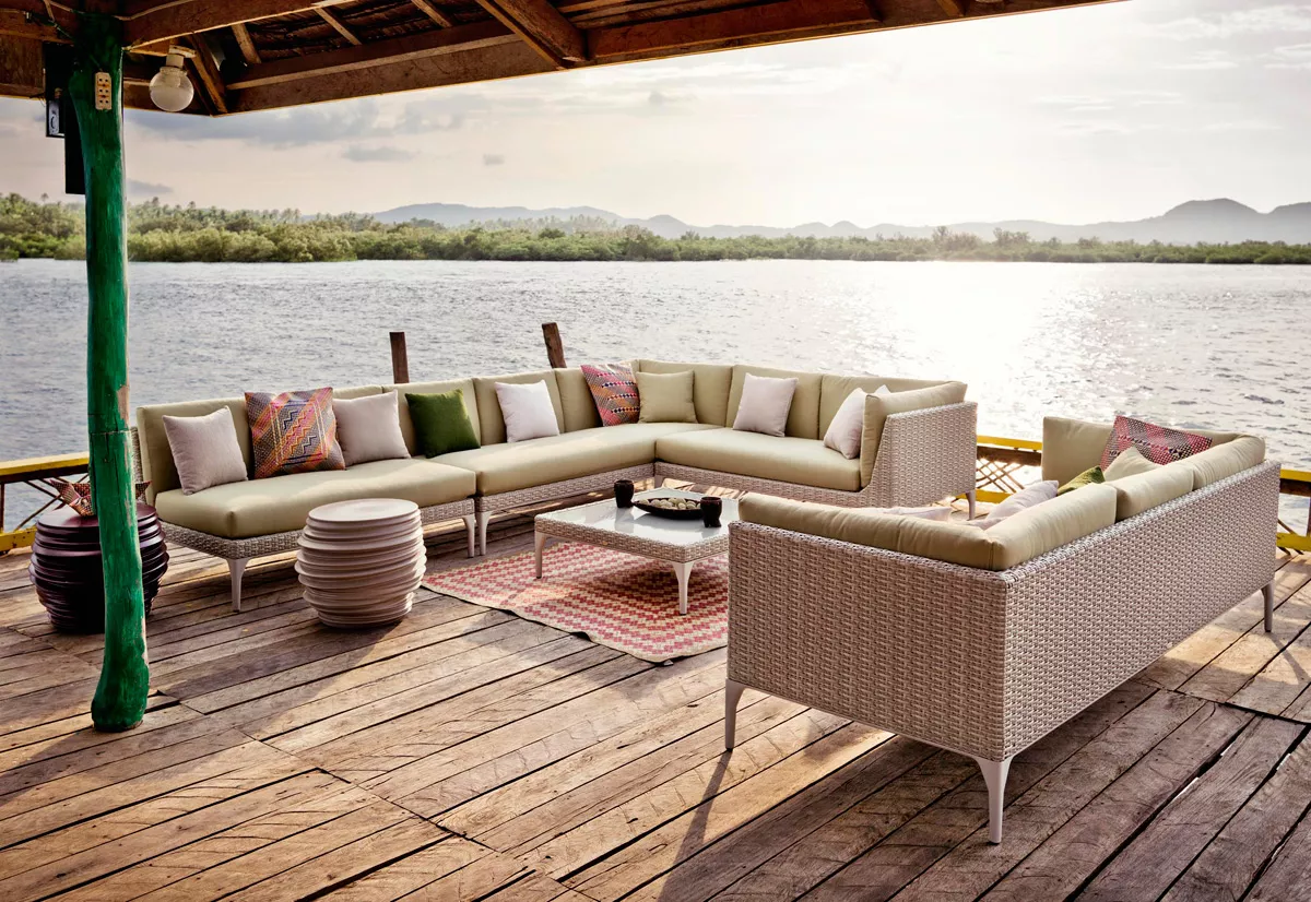 Dedon Mu Kollektion Outdoor Gartenmöbel auf einer Terrasse am See mit Blick auf die Berge im Hintergrund und dekorativen Kissen auf den Sofas