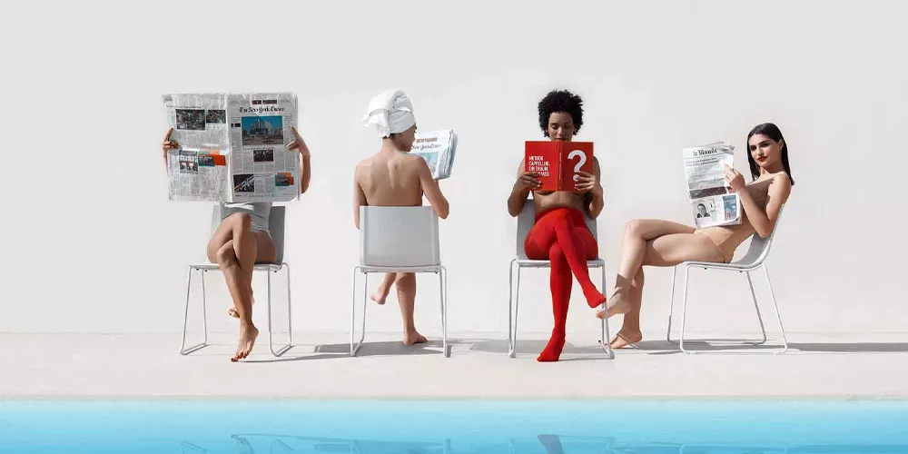 Vier Personen sitzen auf weißen Diabla Vent Stühlen am Pool, lesen Zeitungen und Magazine, vor weißem Hintergrund.