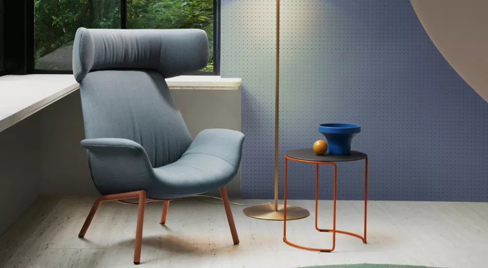 Beistelltisch Pedrali in Schwarz mit orangefarbenem Gestell, neben einem blauen Sessel und einer Stehlampe, vor einer blauen Wand.