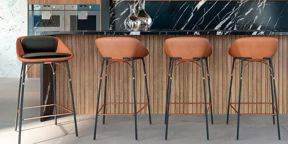 Bargruppe Mayface Nero in Braun vor einer modernen Küchentheke mit Holzverkleidung und schwarzer Marmorplatte, Stimmungsbild.