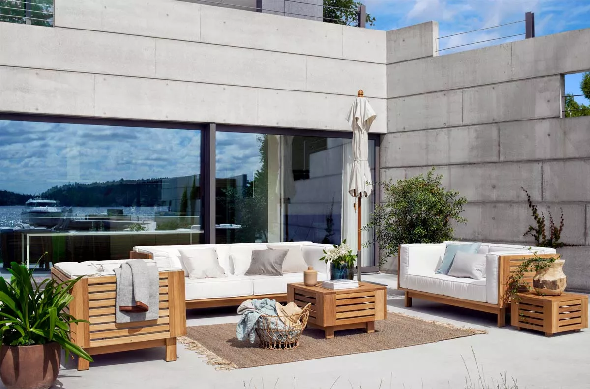 Skargaarden Loungegruppe in Weiß auf moderner Terrasse mit Betonwänden und Blick auf den See, umgeben von Pflanzen und Dekorationen.
