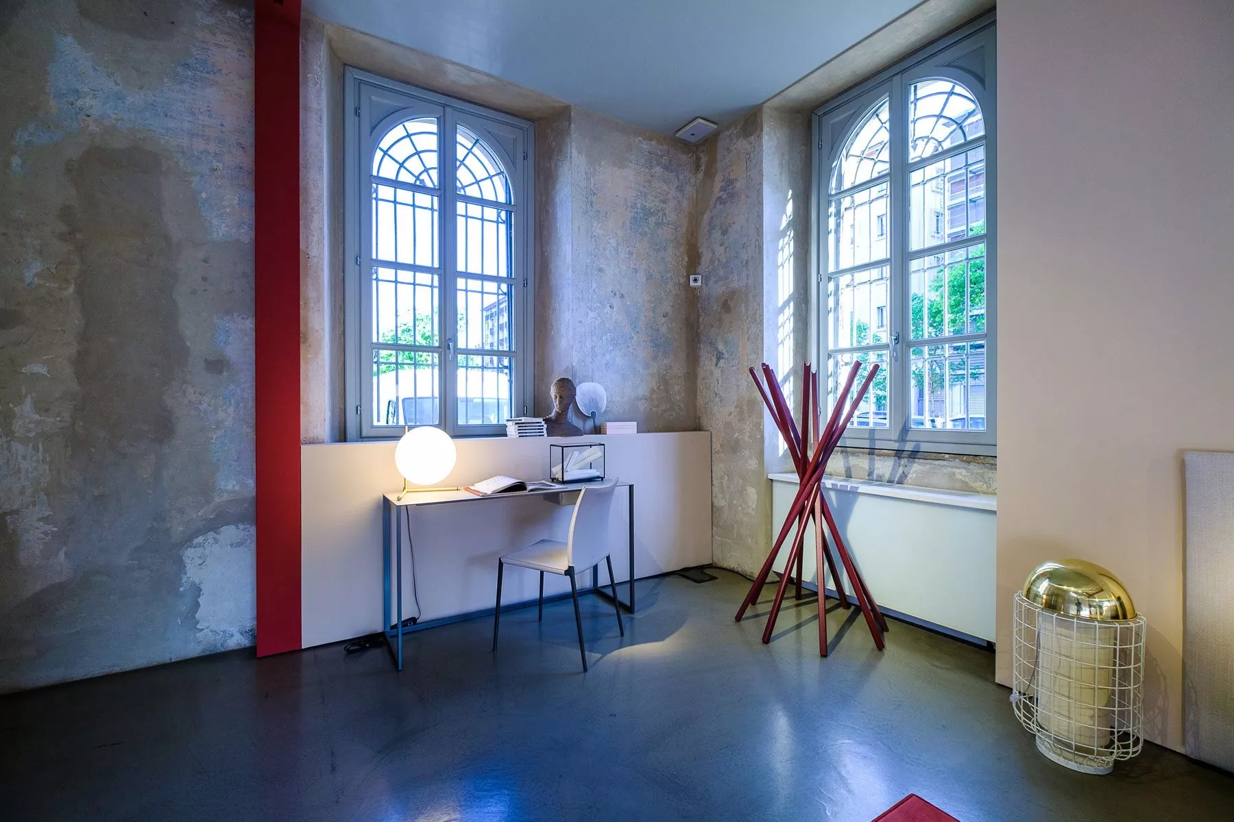 Stimmungsbild eines modernen Raumes mit Zanotta Lia Stuhl in Weiß vor einem Schreibtisch, umgeben von rustikalen Wänden und großen Fenstern.