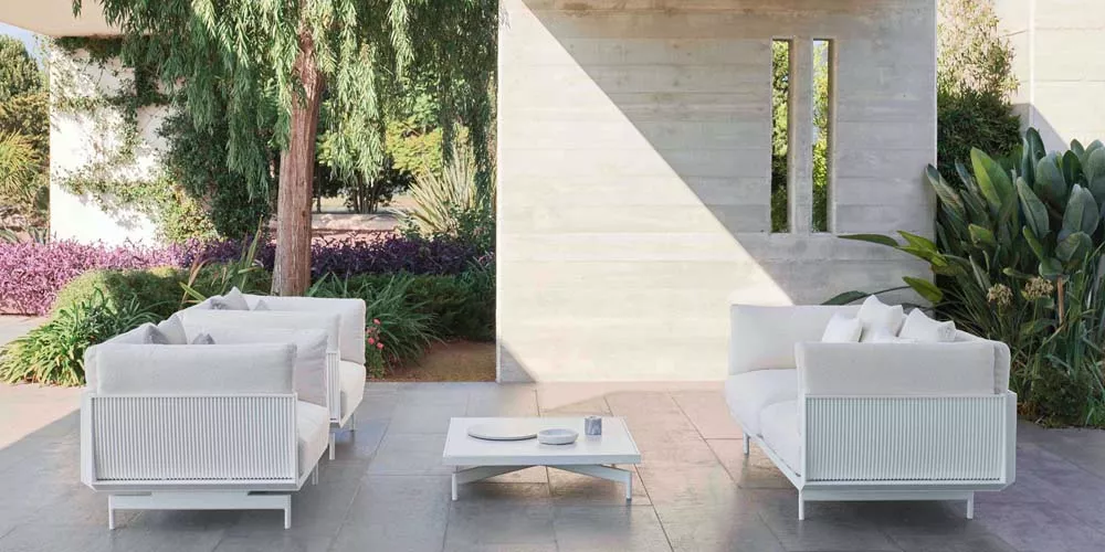 Gandia Blasco Onde Outdoor-Sofa-Set in Weiß auf einer Terrasse mit modernem Hintergrund und Pflanzen im Freien.