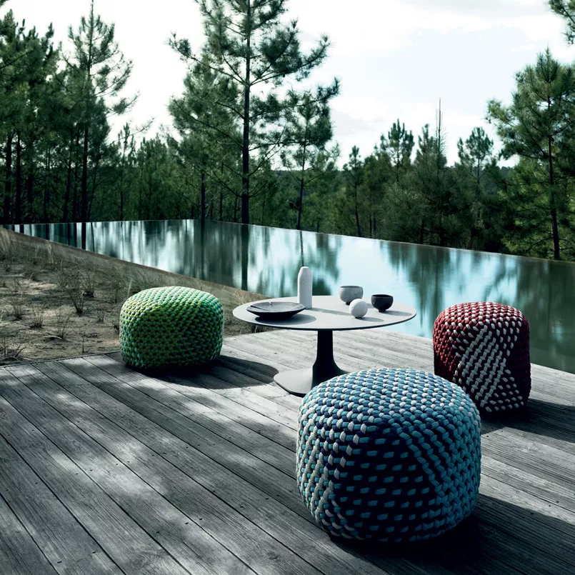 B&B Italia Tramae Hocker in verschiedenen Farben auf einer Terrasse mit Wald und Pool im Hintergrund