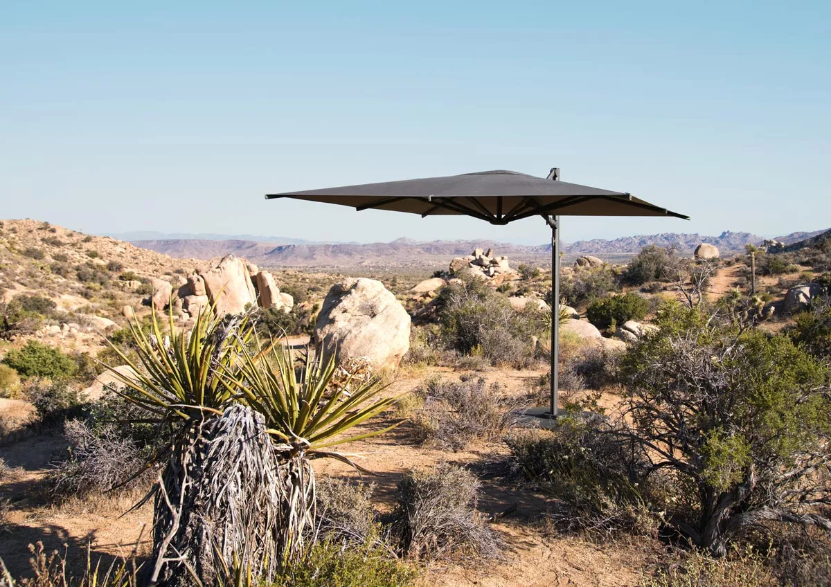 Dedon Reav Square M Cantilever Sonnenschirm inkl Schutzhülle in einer Wüstenlandschaft aufgestellt