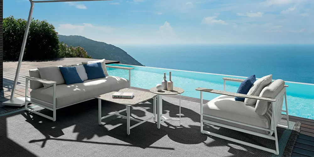 Talenti Riviera Kollektion in Weiß, Outdoor-Sofas und Tisch auf Terrasse mit Meerblick, entspannte Atmosphäre.