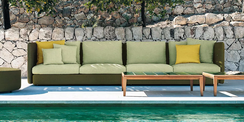 Roda Kollektion Double Sofa in Olivgrün und Hellgrün, Outdoor-Mood-Bild vor einer Steinmauer am Pool.