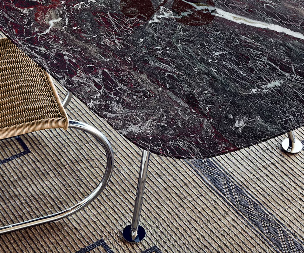 Knoll Grasshopper Tisch mit dunkler Marmorplatte und Stuhl auf gemustertem Teppich in einer stilvollen Wohnumgebung