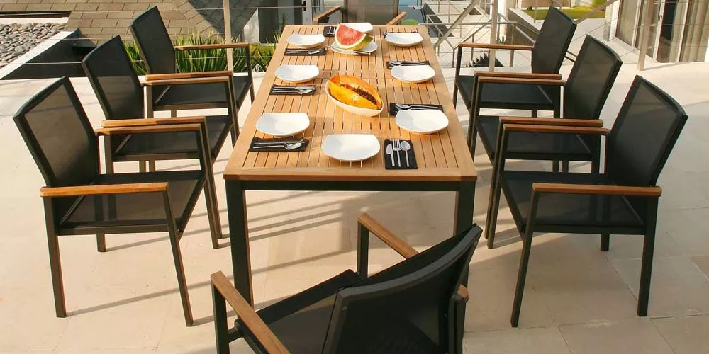 Barlow Tyrie Aura Essgruppe in Schwarz und Holzoptik auf einer Terrasse mit gedecktem Tisch und acht Stühlen, aus Vogelperspektive.