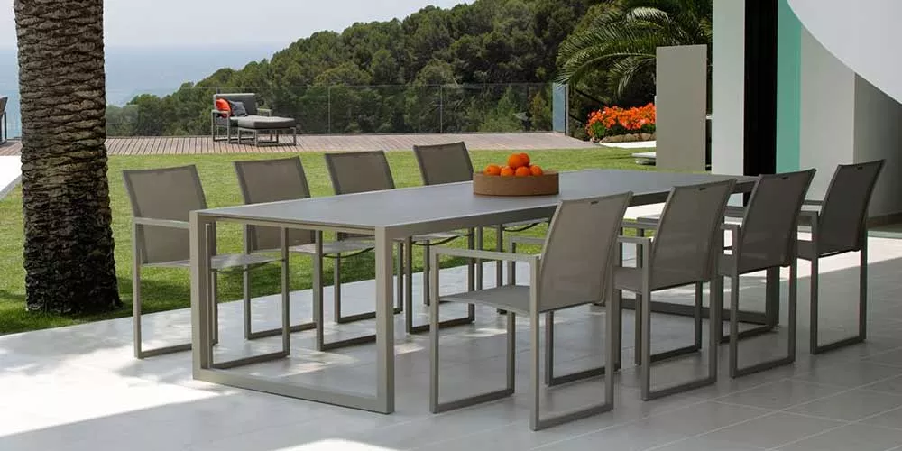 Royal Botania Ninix Essgruppe in Grau auf einer Terrasse mit Meerblick, bestehend aus einem Tisch und acht Stühlen, umgeben von Natur.