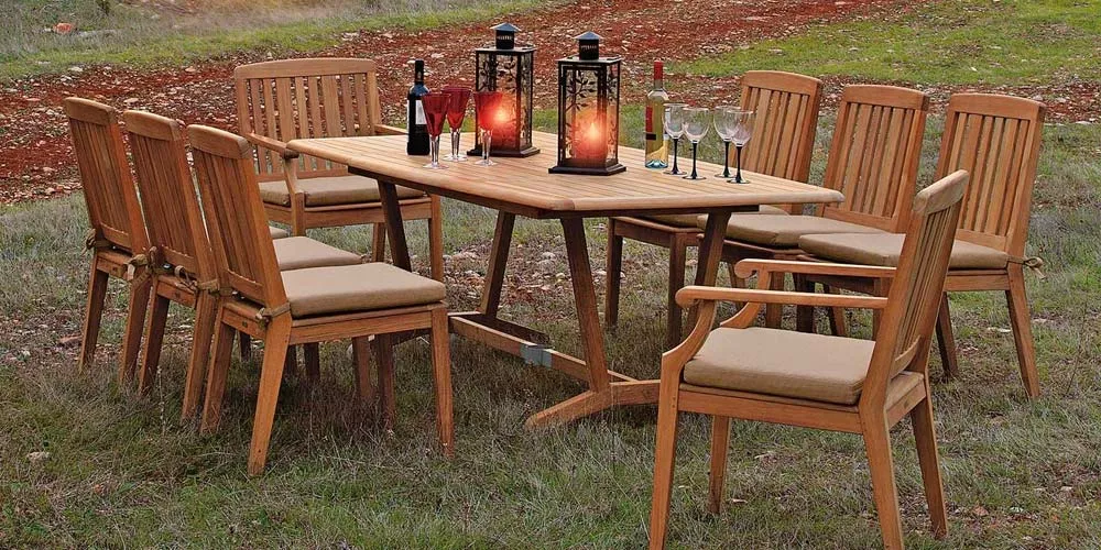 Barlow Tyrie Chesapeake Essgruppe aus Teakholz, bestehend aus einem ovalen Tisch und acht Stühlen, auf einer Wiese arrangiert.