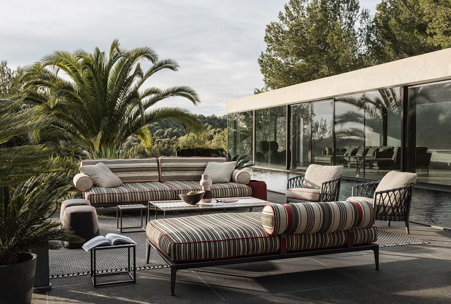 B&B Italia Ribes Outdoor Lounge auf einer Terrasse mit Palmen und modernem Haus im Hintergrund Mood Bild mit entspannten Sitzgelegenheiten