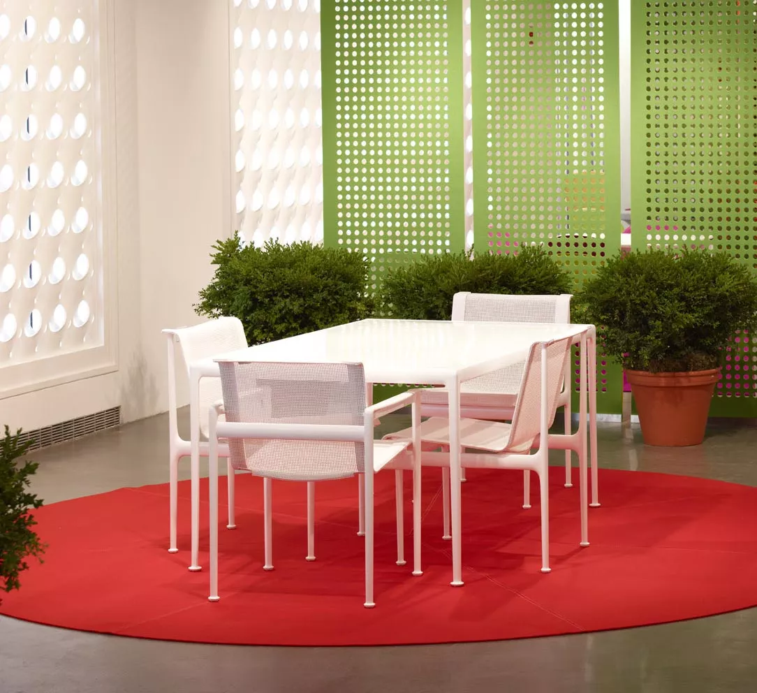 Knoll Studio 1966 Collection Armlehnstuhl in Weiß an einem weißen Tisch auf einem roten Teppich in einem modern eingerichteten Raum mit Pflanzen.