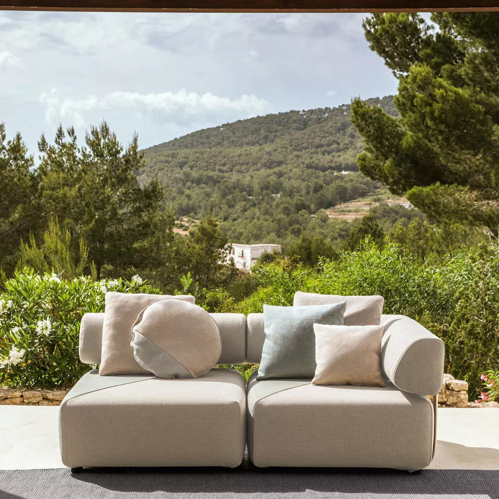 Dedon Brixx Outdoor Loungegruppe in Beige auf Terrasse mit Blick auf bewaldete Hügel und blauen Himmel.
