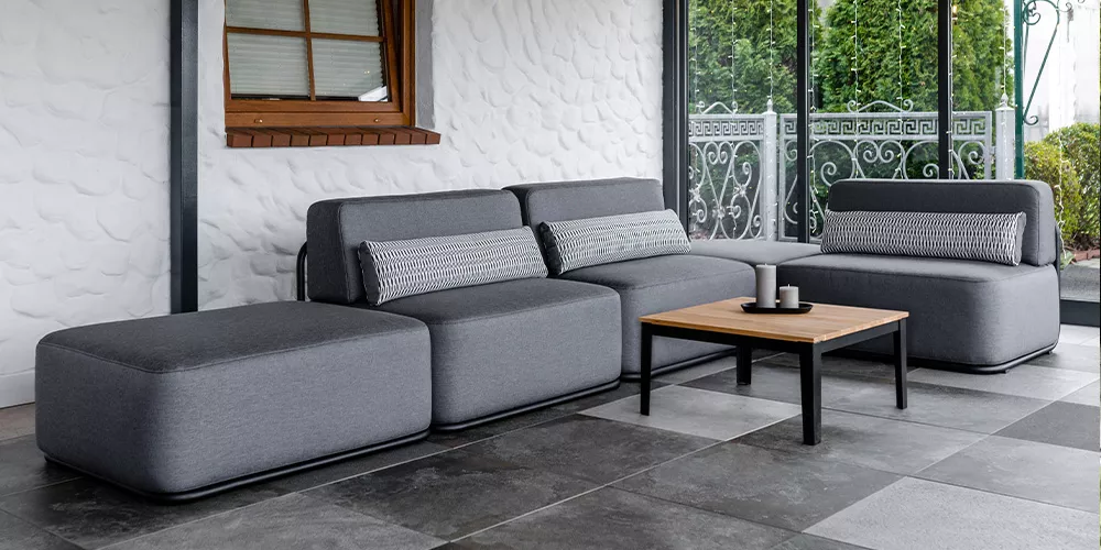 Royal Mirage Lausanne Loungekollektion in Grau auf einer Terrasse mit Steinboden und weißer Wand im Hintergrund.