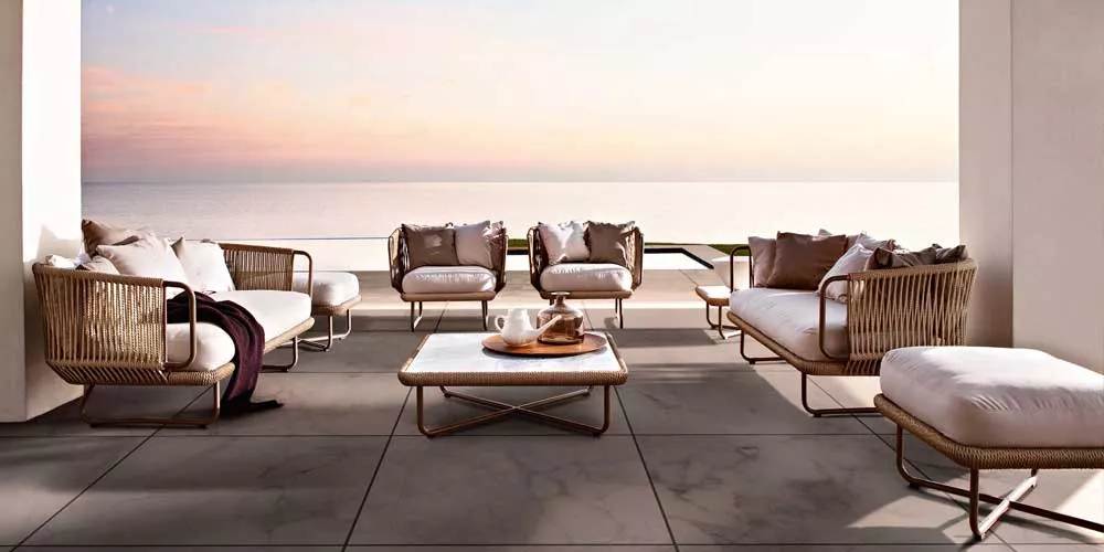 Varaschin Babylon Lounge Gartenmöbel in Naturtönen auf einer Terrasse mit Meerblick bei Sonnenuntergang, gemütliche Atmosphäre.