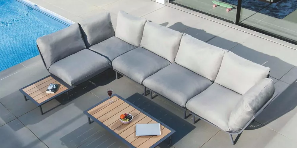 Alexander Rose Beach Lounge in Grau auf einer Terrasse neben einem Pool, mit zwei Beistelltischen und einem Laptop, aus Vogelperspektive.