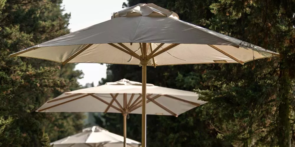 Weißer Weishäupl Basicschirm Sonnenschirm in einem Waldhintergrund, stimmungsvolles Bild mit mehreren Schirmen in einer Reihe.