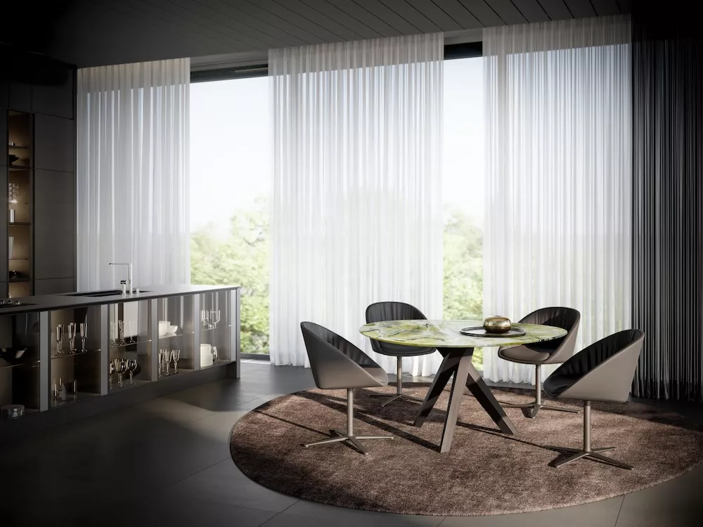 Draenert Dan 2043 Esstisch mit vier Stühlen auf einem runden Teppich in einem modernen Esszimmer mit großen Fenstern und weißen Vorhängen