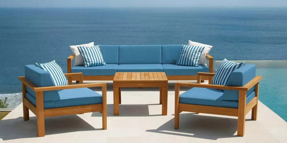 Barlow Tyrie Linear Loungegruppe in Blau auf einer Terrasse mit Meerblick, bestehend aus Sofa, zwei Sesseln und einem Tisch.