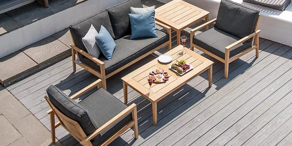 Alexander Rose Tivoli Gartenmöbel-Set in Grau und Holzoptik auf einer Terrasse mit gedecktem Tisch und Kissen, Vogelperspektive.