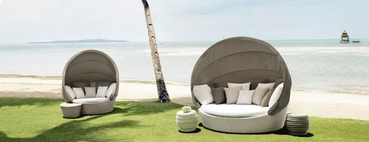 Dedon Orbit XXL Sofainsel in einem Garten am Strand mit Palmen und Meer im Hintergrund