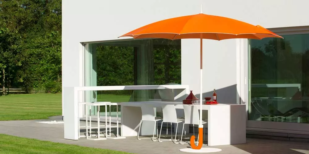Sywawa Gulliver Sonnenschirm in leuchtendem Orange, aufgestellt auf einer modernen Terrasse neben einem weißen Haus.