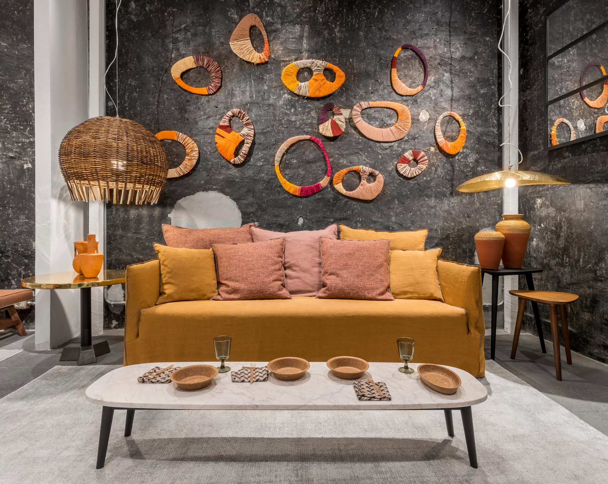 Ein gemütliches Wohnzimmer mit einem Gervasoni Sofa in warmen Farben dekoriert mit bunten Wanddekorationen und einem Couchtisch mit Schalen und Gläsern.